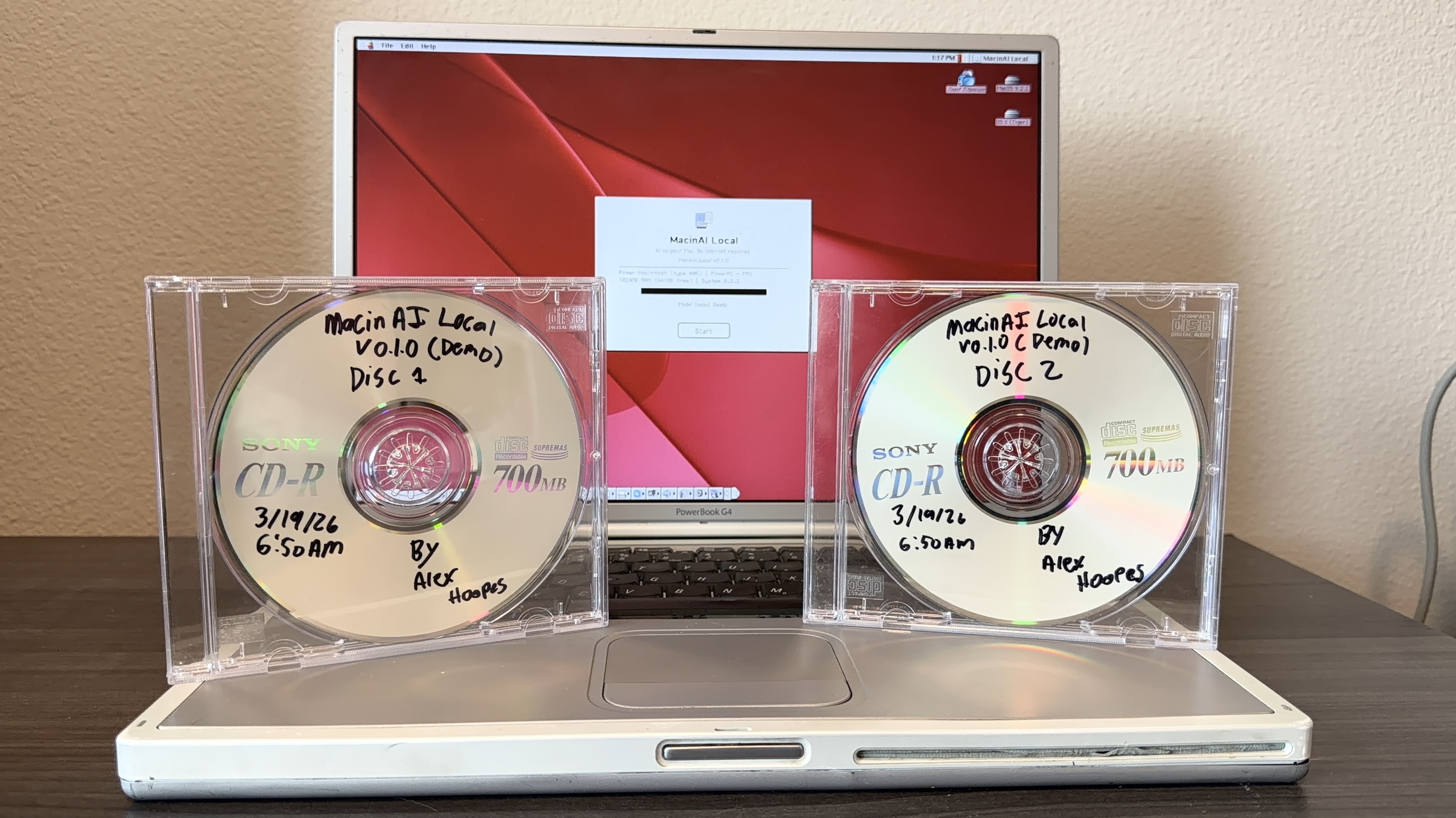 PowerBook G4 Titanium 노트북 앞에 MacinAI Local 설치 CD 두 장이 놓여 있는 모습.